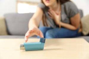 woman with asthma reaching for pump looking for emergency home remedy for asthma attack 300x200